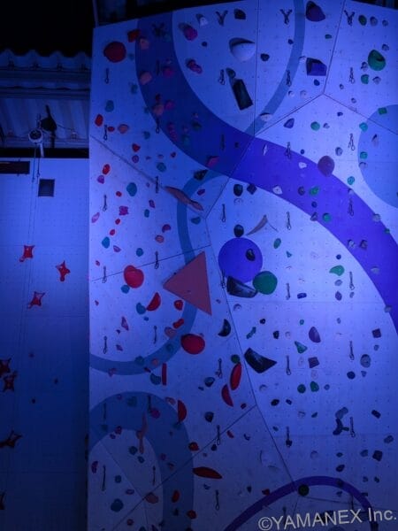 Google Pixel 10a カメラ 青いライトに照らされたボルダリング施設をズーム撮影した一枚